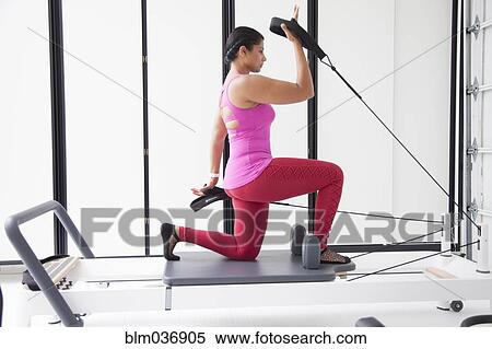 Stock Photography - Asian woman using exercise machine in gymnasium. Fotosearch