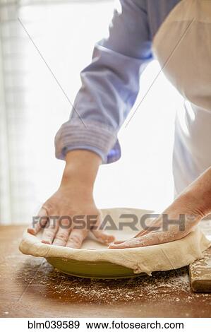Stock Photo - Baker pressing pie dough in dish. Fotosearch