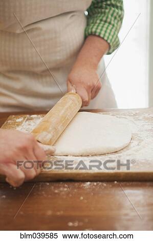 Stock Photography - Baker rolling dough on counter. Fotosearch