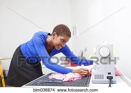 Picture - Black dressmaker using sewing machine. Fotosearch