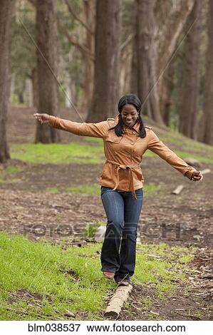Black woman balancing on log in forest View Large Photo Image Stock Photo - Black woman balancing on log in forest. Fotosearch