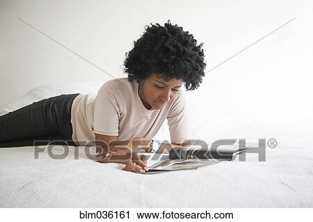 Black woman reading magazine on bed View Large Photo Image Stock Image - Black woman reading magazine on bed. Fotosearch