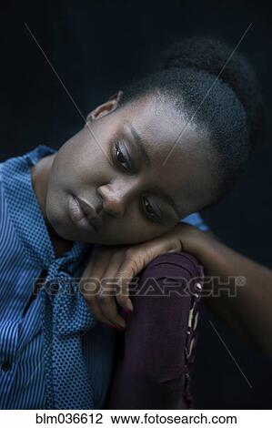 Stock Image - Black woman resting head on armchair. Fotosearch