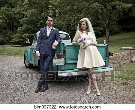 Stock Image - Bride and groom smiling near vintage truck. Fotosearch