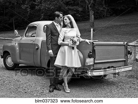 Stock Image - Bride and groom smiling near vintage truck. Fotosearch