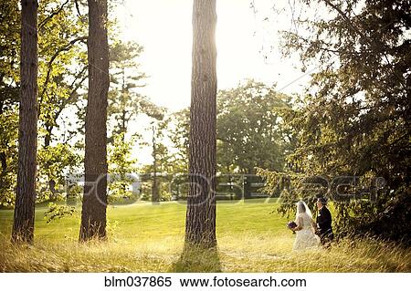 Stock Photography - Bride and groom walking in rural field. Fotosearch
