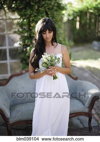 Bride holding bouquet of flowers in backyard View Large Photo Image Picture - Bride holding bouquet of flowers in backyard. Fotosearch