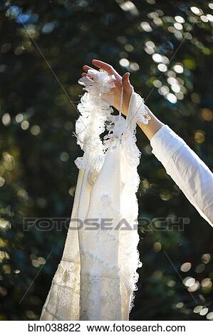 Bride holding wedding gown in garden View Large Photo Image Stock Image - Bride holding wedding gown in garden. Fotosearch