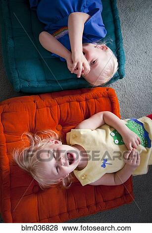 Stock Photo - Brother and sister playing on cushions on floor. Fotosearch
