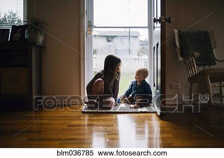 Stock Photography - Brother and sister sitting in doorway. Fotosearch