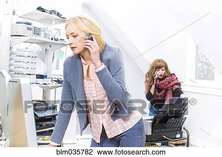 Businesswomen talking on cell phone in office View Large Photo Image Stock Image - Businesswomen talking on cell phone in office. Fotosearch