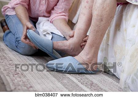 Stock Photo - Caregiver helping older woman in home. Fotosearch