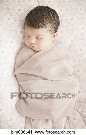 Stock Image - Caucasian baby girl swaddled in blanket. Fotosearch