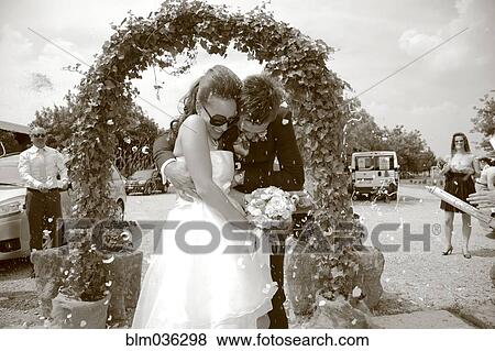 Caucasian bride and groom walking through archway View Large Photo Image Stock Photo - Caucasian bride and groom walking through archway. Fotosearch