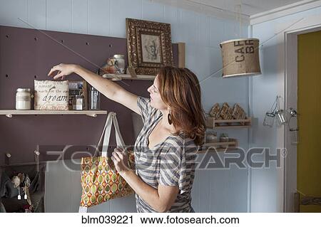 Stock Image - Caucasian business owner arranging items in store. Fotosearch