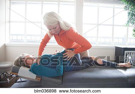 Stock Photo - Caucasian chiropractor stretching back of client. Fotosearch