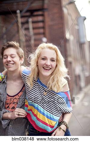 Stock Photo - Caucasian couple laughing on city sidewalk. Fotosearch