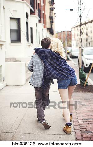 Stock Photograph - Caucasian couple walking on city sidewalk. Fotosearch