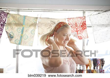 Stock Photo - Caucasian customer tying headscarf in store. Fotosearch