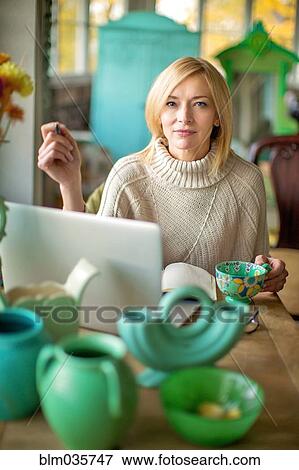 Stock Photo - Caucasian entrepreneur using laptop in shop. Fotosearch