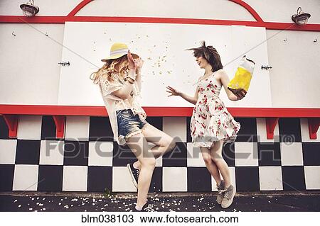 Stock Image - Caucasian friends having popcorn fight outdoors. Fotosearch