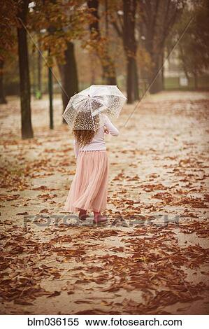 Caucasian girl carrying umbrella in park View Large Photo Image Stock Photography - Caucasian girl carrying umbrella in park. Fotosearch