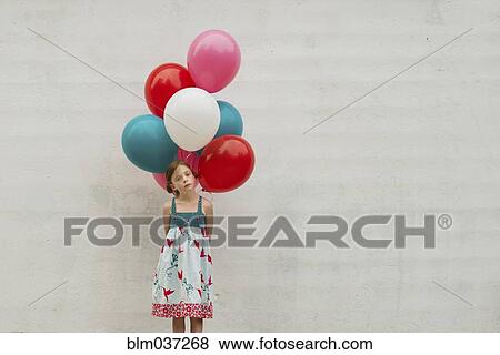Stock Photo - Caucasian girl holding bunch of balloons. Fotosearch