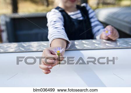 Stock Photo - Caucasian girl holding flowers in truck bed. Fotosearch