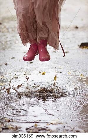 Caucasian girl in rain boots jumping in rain puddles View Large Photo Image Stock Photo - Caucasian girl in rain boots jumping in rain puddles. Fotosearch