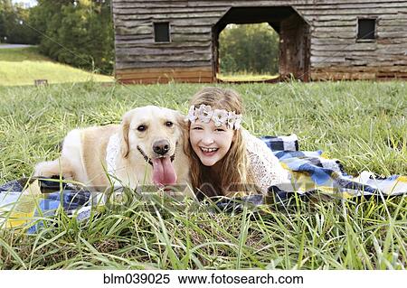 Stock Photography - Caucasian girl laying on blanket with dog. Fotosearch