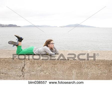 Caucasian girl laying on concrete wall over ocean View Large Photo Image Stock Photo - Caucasian girl laying on concrete wall over ocean. Fotosearch