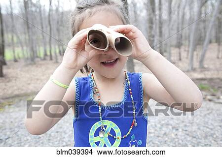Picture - Caucasian girl playing with cardboard tubes in forest. Fotosearch