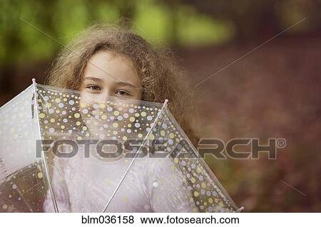 Stock Photo - Caucasian girl playing with umbrella outdoors. Fotosearch