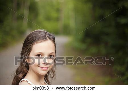 Stock Photo - Caucasian girl smiling on dirt road. Fotosearch