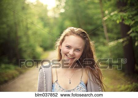 Stock Image - Caucasian girl smiling on forest path. Fotosearch