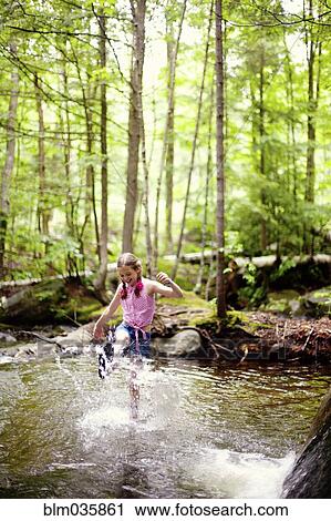 Stock Image - Caucasian girl splashing in river. Fotosearch