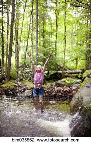 Stock Image - Caucasian girl splashing in river. Fotosearch