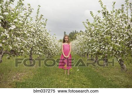 Stock Photography - Caucasian girl standing in blooming orchard. Fotosearch