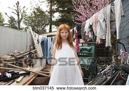 Stock Photography - Caucasian girl standing in dilapidated backyard. Fotosearch