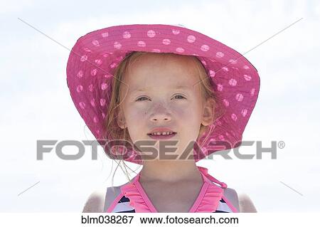 Stock Photo - Caucasian girl wearing sun hat under sky. Fotosearch