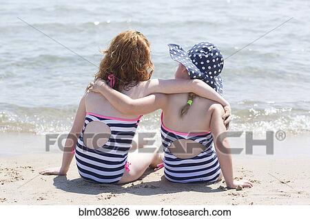 Stock Photograph - Caucasian girls hugging on beach. Fotosearch
