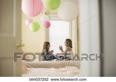Stock Image - Caucasian girls playing clapping game in bedroom. Fotosearch