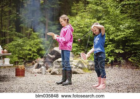Stock Photo - Caucasian girls playing with toys in forest. Fotosearch