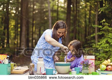 Stock Photograph - Caucasian mother and daughter cooking in forest. Fotosearch