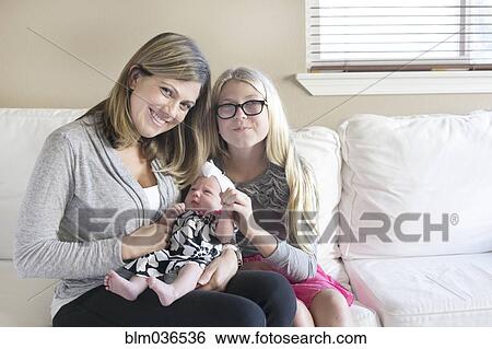 Caucasian mother and daughter cuddling newborn on sofa View Large Photo Image Stock Photograph - Caucasian mother and daughter cuddling newborn on sofa. Fotosearch