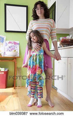 Stock Photo - Caucasian mother and daughter hugging in kitchen. Fotosearch