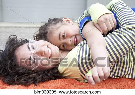 Stock Photography - Caucasian mother and daughter hugging on carpet. Fotosearch