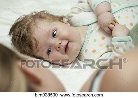 Stock Image - Caucasian mother and daughter laying on bed. Fotosearch