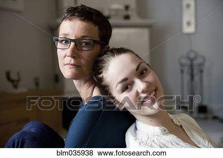 Stock Photo - Caucasian mother and daughter sitting back to back. Fotosearch