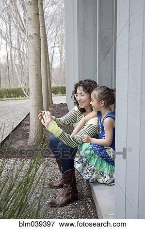 Stock Photo - Caucasian mother and daughter taking selfie with cell phone. Fotosearch